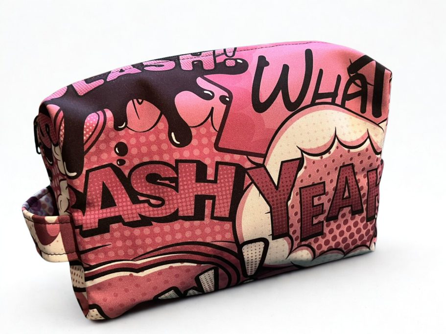 Bunte Kosmetiktasche mit Comic-Design in Pink und auffälligen Schriftzügen.
