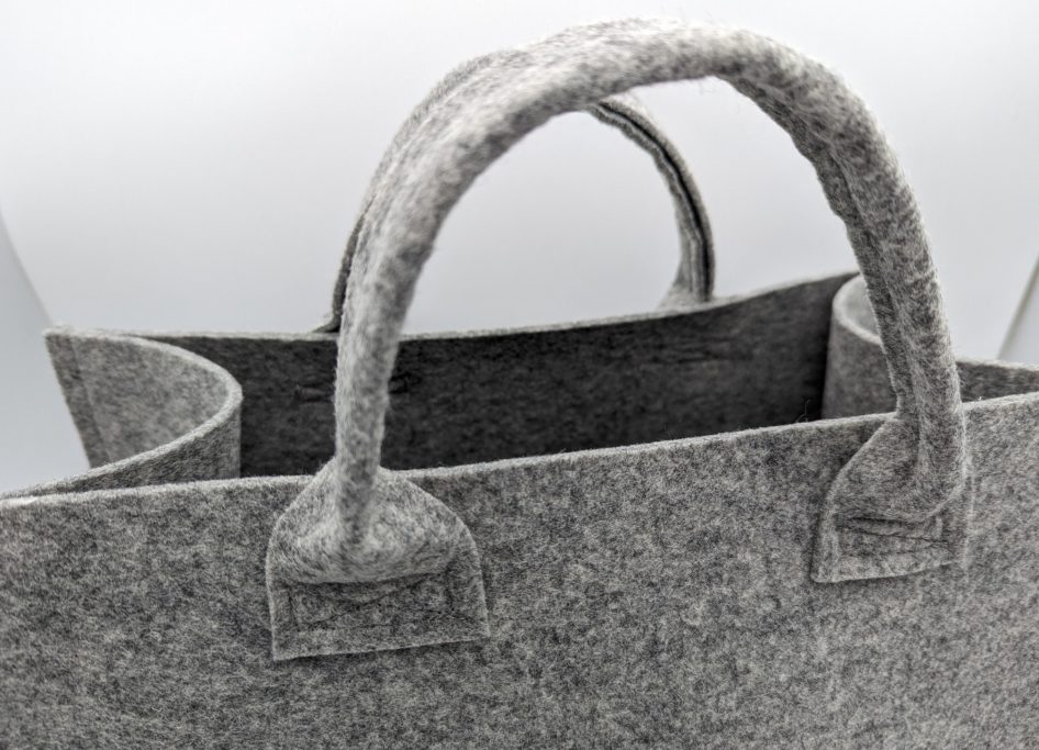 Grau filzene Tasche mit zwei Griffen und offener Oberseite.