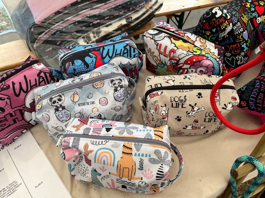 Bunte Kosmetiktaschen mit verschiedenen Mustern und Motiven auf einem Tisch.