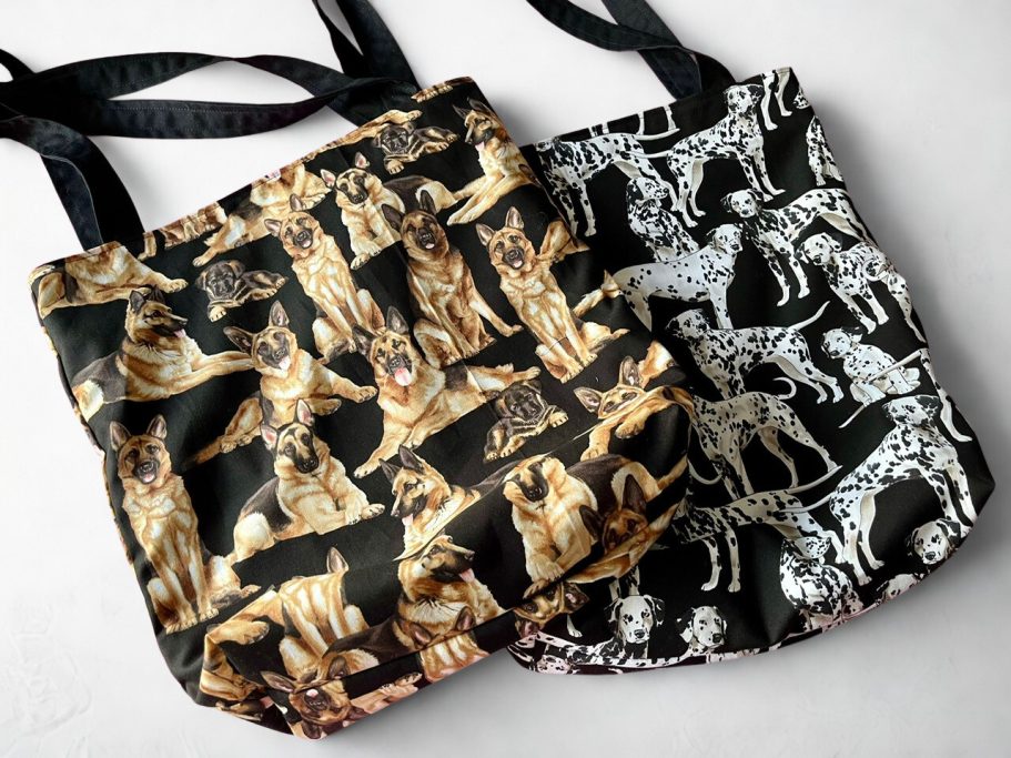 Zwei Einkaufstaschen mit verschiedenen Hunden auf schwarzem Hintergrund.