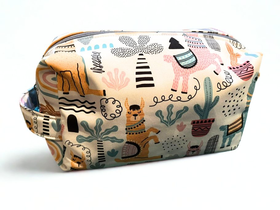 Kosmetiktasche mit buntem Tier- und Pflanzenmotiv auf hellem Hintergrund.