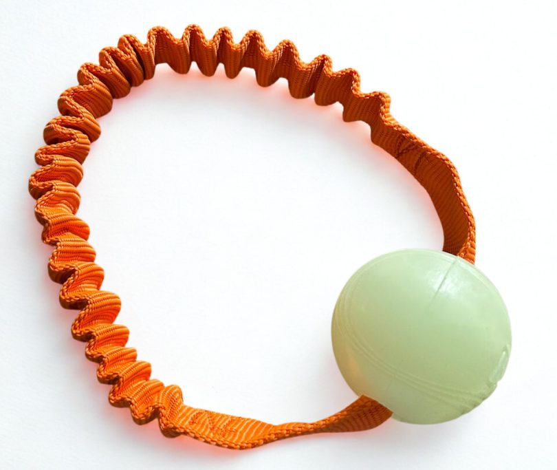 Orange elastischer Band mit einem grünen Ball.